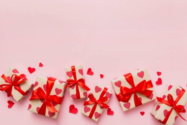 Top view photo of valentine day decorations gift box with red ribbon bow on colored background. Holiday gift boxes with top view.