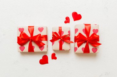 Top view photo of valentine day decorations gift box with red ribbon bow on colored background. Holiday gift boxes with top view.