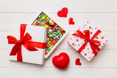 Valentine day composition: sweet candy, with gift boxes with bow and red felt hearts, photo template, background. Top View with copy space.