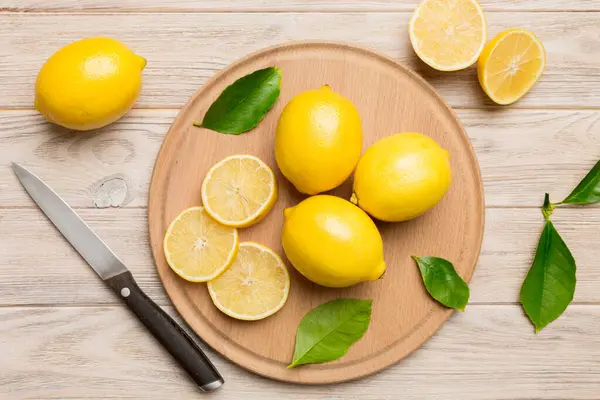 Kesme tahtasındaki taze ve olgun limonlar için fotokopi alanı olan üst manzara. Sağlıklı yemek geçmişi. Limon ve limon dilimlerinin, sıkacağı ve bıçak renginde arka planı çok zarif..