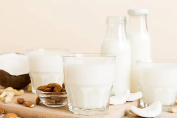 Set or collection of various vegan milk almond, coconut, cashew, on table background. Vegan plant based milk and ingredients, top view.