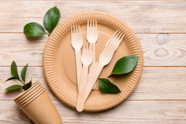 Açık beyaz masa arkaplanındaki boş, tek kullanımlık çevre dostu tabaklar, bardaklar, çatal bıçaklar. Üst Manzara. Biyo-çözünebilir el yapımı yemekler. Geri dönüşüm konsepti. Yakın plan..