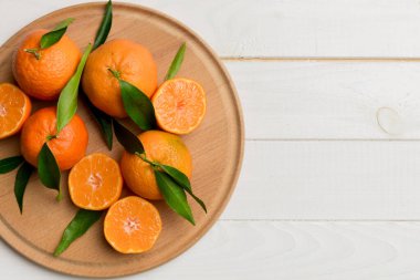 Taze kesilmiş mandalinalar ve renkli arka planda yuvarlak tabaklar. Yemek ve içecek malzemeleri hazırlanıyor. Sağlıklı beslenme teması üst görünüm kopyalama alanı.