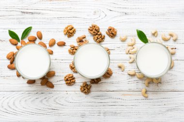 Masa arkasında çeşitli vejetaryen süt bademi, kaju fıstığı seti ya da koleksiyonu. Vejetaryen bitkisi sütü ve malzemeleri, üst görünüm.