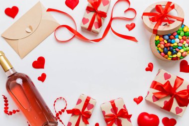 top view photo of st valentine day decor shopping, bag, wine, bottle, envelope, gift, box, candy and red heart on colored background with empty space. Frame background.