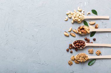 mixed nuts in white wooden spoon. Mix of various nuts on colored background. pistachios, cashews, walnuts, hazelnuts, peanuts and brazil nuts.