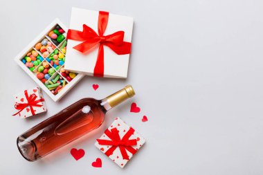 Sevgililer Günü için renkli arka planda bir şişe kırmızı şarap hediye ve çikolatalı. Kalp, hediye kutusuyla şekillendirilmiş çikolatalar fotokopi alanı ile üst görünüm.