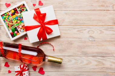 Sevgililer Günü için renkli arka planda bir şişe kırmızı şarap hediye ve çikolatalı. Kalp, hediye kutusuyla şekillendirilmiş çikolatalar fotokopi alanı ile üst görünüm.