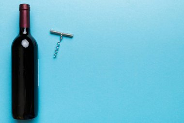 Renkli masada tirbuşonlu bir şişe kırmızı şarap. Düz konum, üst görünüm kopyalama alanı.