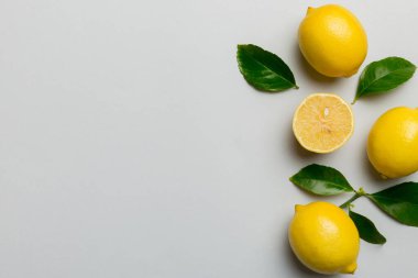 Renkli arka planda yeşil yapraklı taze limonlar, üst görünüm, metin için boşluk.