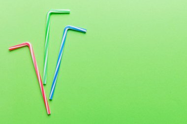 Renkli arka planda parti için pipet içmek. Yaz kokteylleri için renkli plastik tek kullanımlık pipetlerin en üst görüntüsü. kopyalama alanı olan meyve suyu için farklı pipetler.