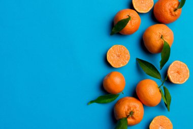 Renkli arkaplanda yeşil yaprakları, üst görünümü, metin için alanı olan bir sürü olgun mandalina..