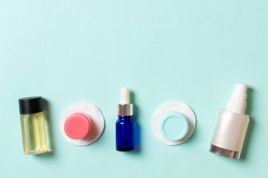 Yüz bakımı için en iyi bakış açısı: şişeler ve kavanozlar dolusu tonik, su, krem, renkli arka planda pamuk pedleri. Fikirleriniz için boş midye içeren vücut bakım konsepti.