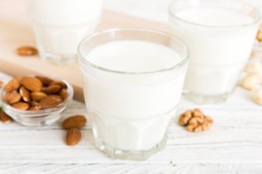 Masa arkasında çeşitli vejetaryen süt bademi, kaju fıstığı seti ya da koleksiyonu. Vejetaryen bitkisi sütü ve malzemeleri, üst görünüm.