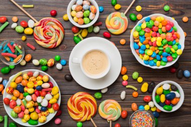 Coffee cup with chocolates and colored candy. Top view on table background with copy space.