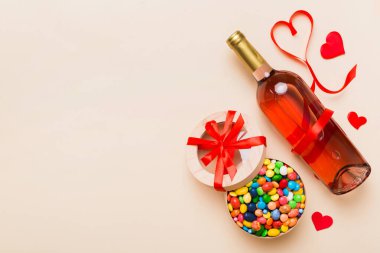 Sevgililer Günü için renkli arka planda bir şişe kırmızı şarap hediye ve çikolatalı. Kalp, hediye kutusuyla şekillendirilmiş çikolatalar fotokopi alanı ile üst görünüm.