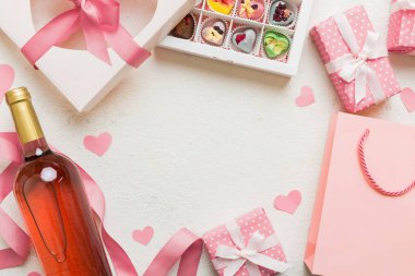 top view photo of st valentine day decor shopping, bag, wine, bottle, envelope, gift, box, candy and red heart on colored background with empty space. Frame background.