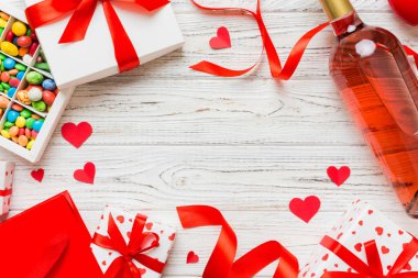 top view photo of st valentine day decor shopping, bag, wine, bottle, envelope, gift, box, candy and red heart on colored background with empty space. Frame background.