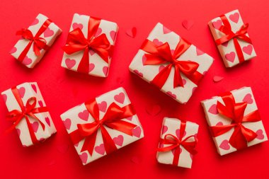 Top view photo of valentine day decorations gift box with red ribbon bow on colored background. Holiday gift boxes with top view.