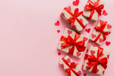 Top view photo of valentine day decorations gift box with red ribbon bow on colored background. Holiday gift boxes with top view.