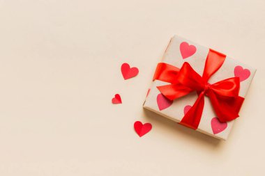 Top view photo of valentine day decorations gift box with red ribbon bow on colored background. Holiday gift boxes with top view.