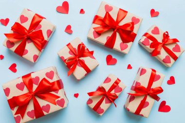Top view photo of valentine day decorations gift box with red ribbon bow on colored background. Holiday gift boxes with top view.