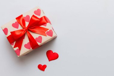 Top view photo of valentine day decorations gift box with red ribbon bow on colored background. Holiday gift boxes with top view.