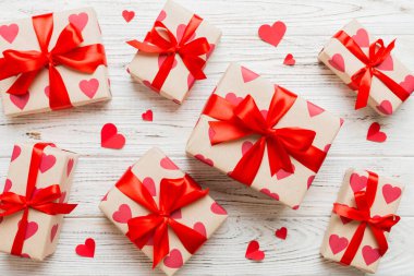 Top view photo of valentine day decorations gift box with red ribbon bow on colored background. Holiday gift boxes with top view.