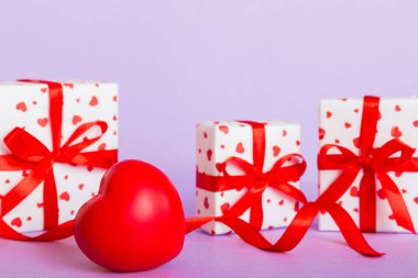 gift box with red bow and red heart on colored background. Perspective view. Flat lay.