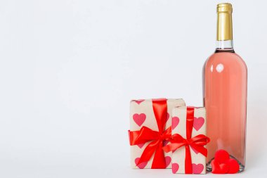 Bottle of wine on colored background for Valentine Day with gift box. Heart shaped with presrnt box perspective view with copy space.