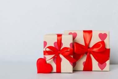 gift box with red bow and red heart on colored background. Perspective view. Flat lay.