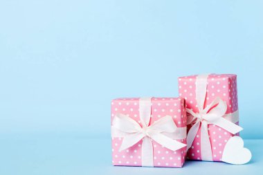 gift box with red bow and red heart on colored background. Perspective view. Flat lay.