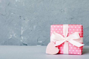 gift box with red bow and red heart on colored background. Perspective view. Flat lay.