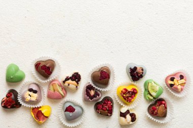 chocolate sweets in the form of a heart with fruits and nuts on a colored background. top view with space for text, holiday concept.