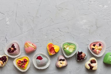 chocolate sweets in the form of a heart with fruits and nuts on a colored background. top view with space for text, holiday concept.