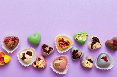 chocolate sweets in the form of a heart with fruits and nuts on a colored background. top view with space for text, holiday concept.