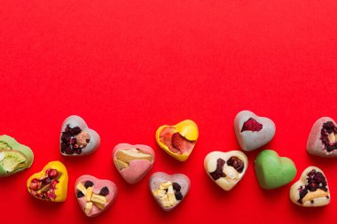 chocolate sweets in the form of a heart with fruits and nuts on a colored background. top view with space for text, holiday concept.