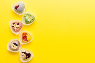chocolate sweets in the form of a heart with fruits and nuts on a colored background. top view with space for text, holiday concept.