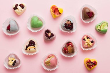 chocolate sweets in the form of a heart with fruits and nuts on a colored background. top view with space for text, holiday concept.