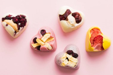 chocolate sweets in the form of a heart with fruits and nuts on a colored background. top view with space for text, holiday concept.