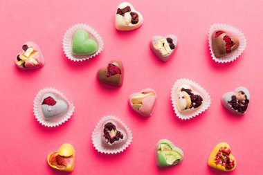 chocolate sweets in the form of a heart with fruits and nuts on a colored background. top view with space for text, holiday concept.