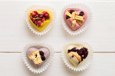 chocolate sweets in the form of a heart with fruits and nuts on a colored background. top view with space for text, holiday concept.