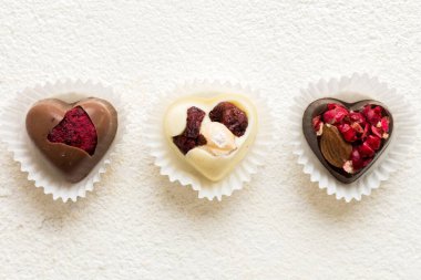 chocolate sweets in the form of a heart with fruits and nuts on a colored background. top view with space for text, holiday concept.