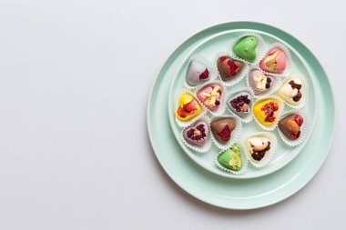 Plate with different chocolate on colored background. Assortment of fine chocolates top view vith copy space Health and obesity concept.