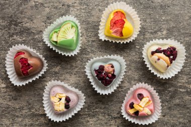 chocolate sweets in the form of a heart with fruits and nuts on a colored background. top view with space for text, holiday concept.
