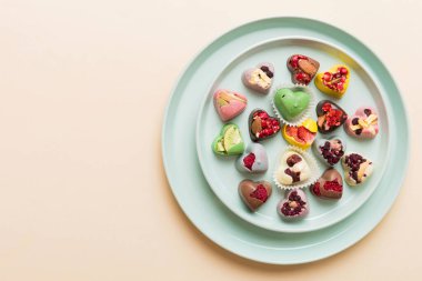 Plate with different chocolate on colored background. Assortment of fine chocolates top view vith copy space Health and obesity concept.