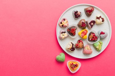 Plate with different chocolate on colored background. Assortment of fine chocolates top view vith copy space Health and obesity concept.