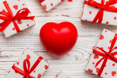 gift box with red bow and red heart on colored background . Top view. Flat lay.