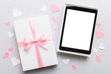 Gift box of open tablet for the holidays with a bow top view.