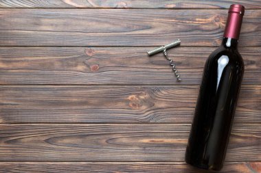 Renkli masada tirbuşonlu bir şişe kırmızı şarap. Düz konum, üst görünüm kopyalama alanı.